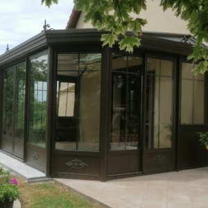 véranda grise en aluminium à pans coupés et toiture périmétrique adossée à maison sur terrasse
