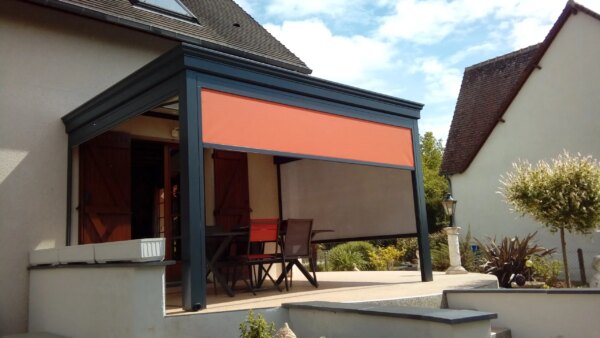 Pergola Gris Anthracite avec stores oranges sur terrasse en béton surélevé