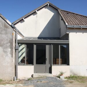 véranda en alu sur mesure entre deux pans de maisons gris antracite